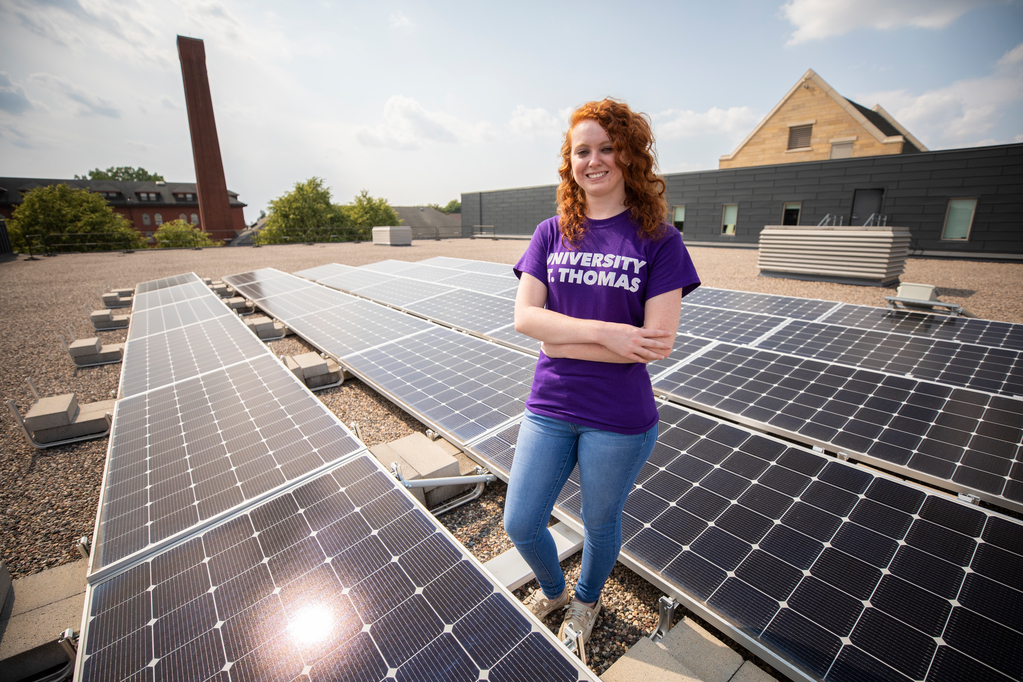 Electrical Engineering student Rachel Pietsch poses for photos by the microgrid center's solar panels on the rooftop of the campus gym.