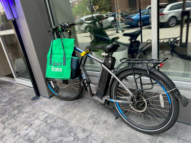 An e-bike with an Uber Eats bag hanging from the handlebars leans against a building.